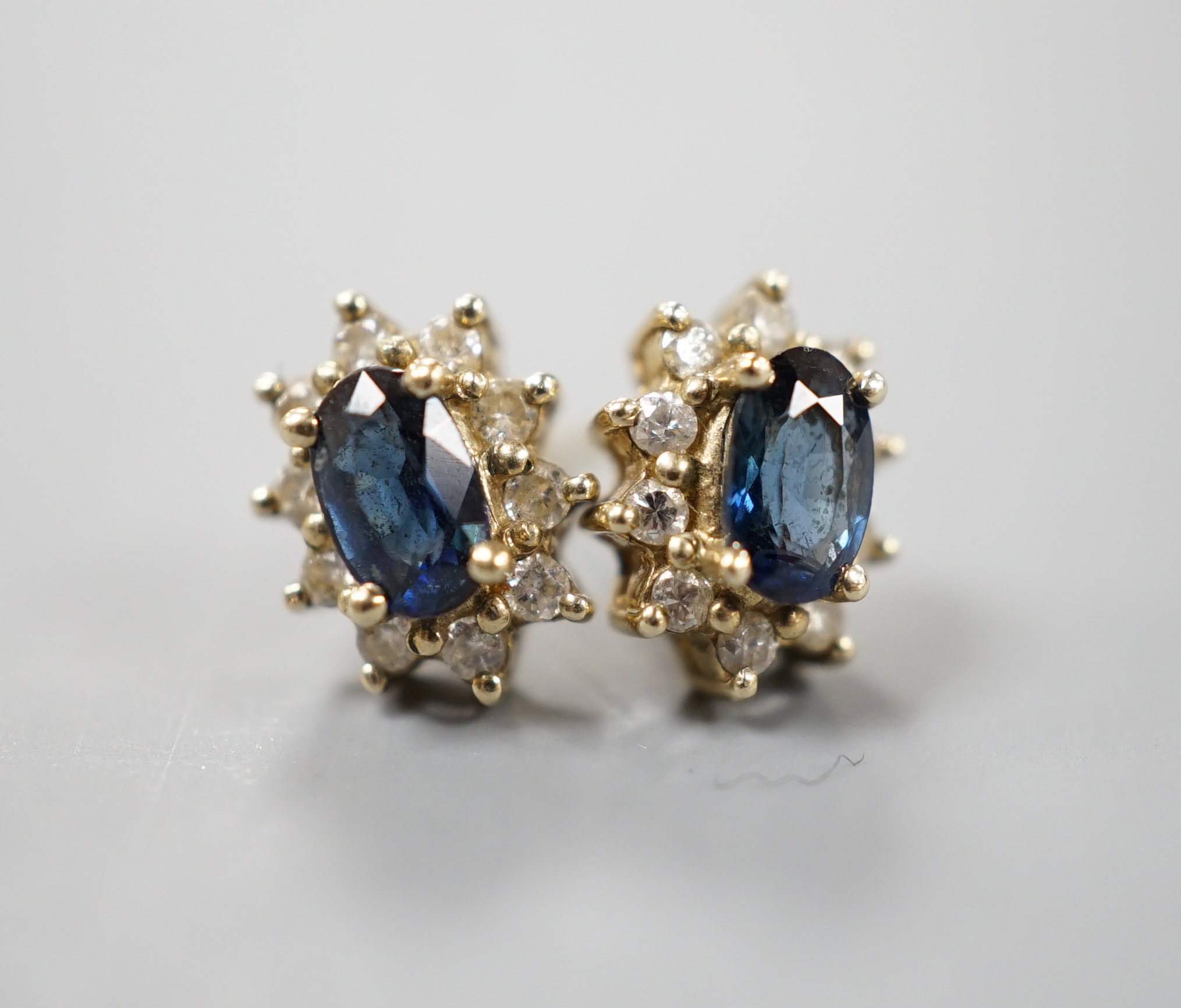 A pair of modern 9ct gold, sapphire and diamond chip set oval cluster earrings, gross 1.3 grams.